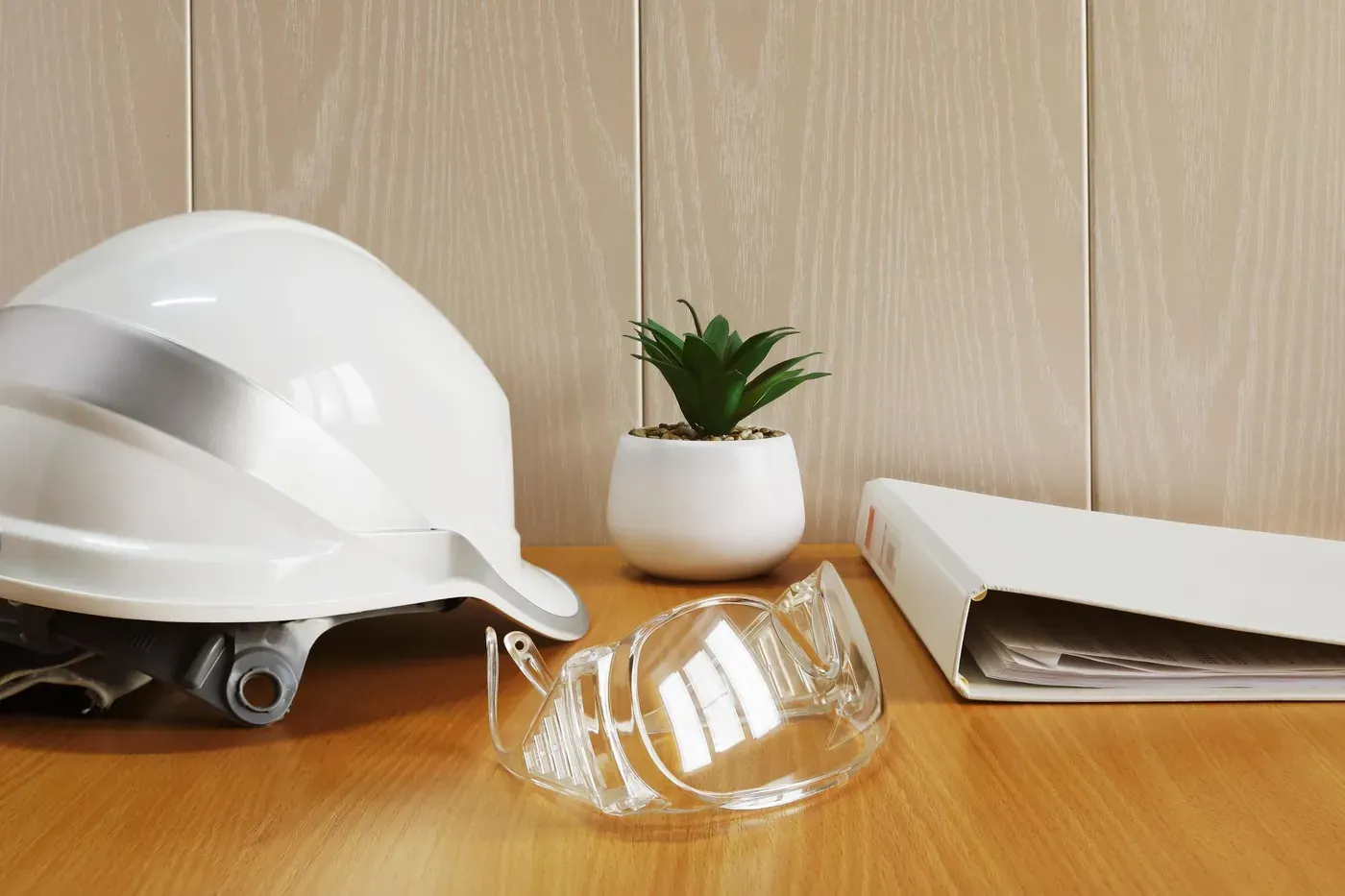 Consultoría SST: casco de seguridad, gafas y documentos sobre la mesa
